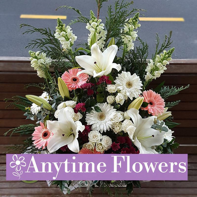 A serene bouquet of white lilies, gerberas, and roses with lush greenery.