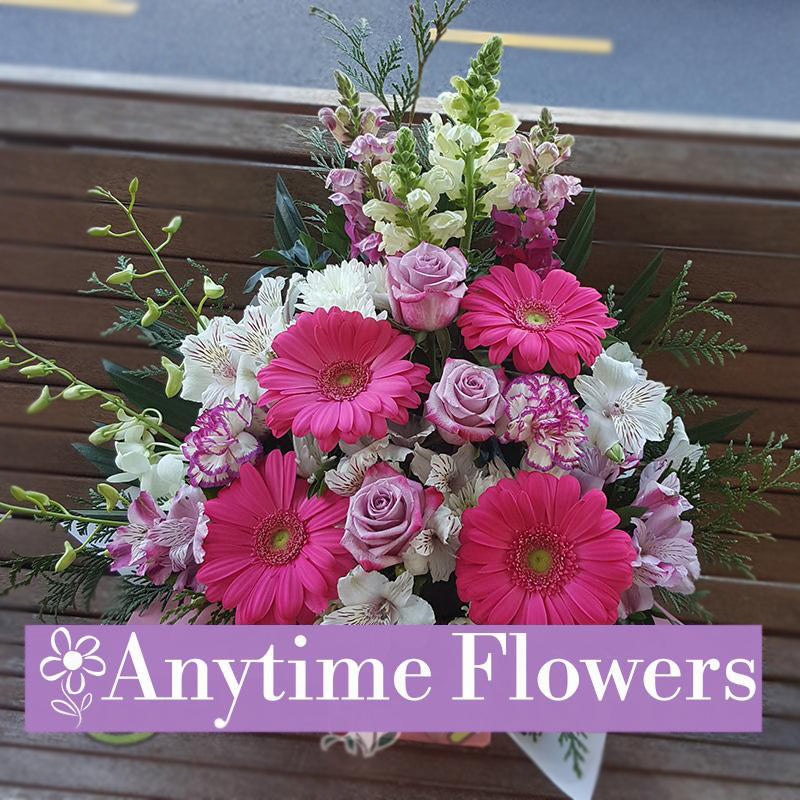A vibrant bouquet featuring bold pink gerberas, lavender roses, and snapdragons, accented with fresh greenery.
