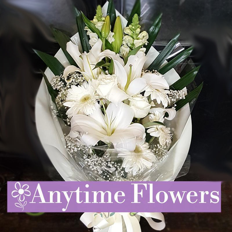 A stunning bouquet of white lilies, roses, and gerberas, accented with baby's breath and greenery.