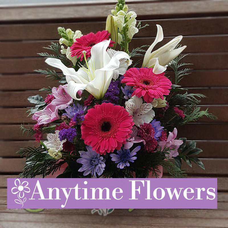An elegant bouquet featuring vibrant pink gerberas, pastel blooms, and lush greenery.