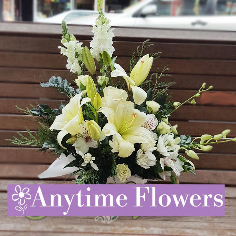 A serene bouquet featuring white lilies, roses, and snapdragons, accented with lush greenery for a timeless and elegant design.