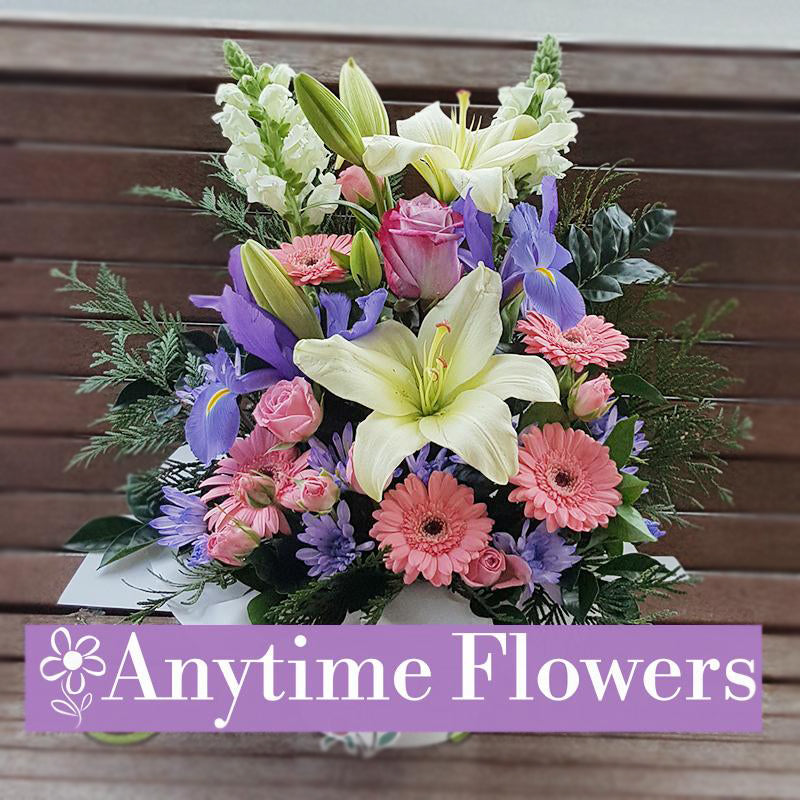 A graceful bouquet featuring white lilies, pink gerberas, purple irises, and pink roses, accented with lush greenery for an elegant design.