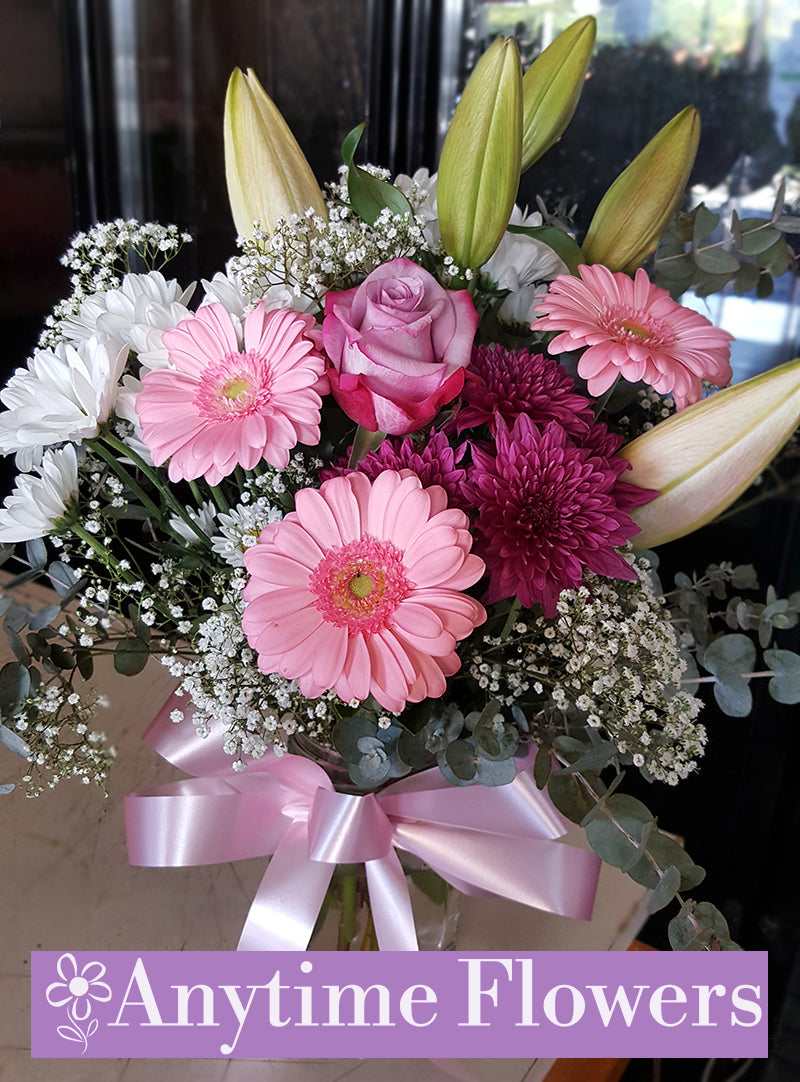 A tranquil vase arrangement featuring white lilies, pink gerberas, and lavender roses.