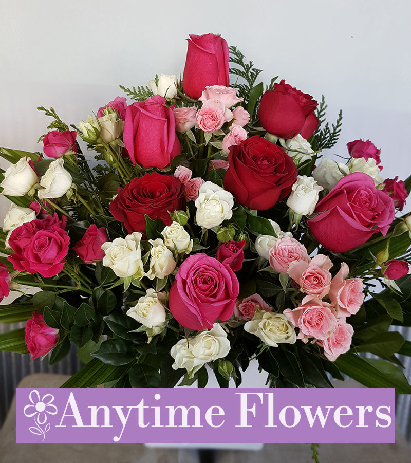 Romantic bouquet of red, pink, and white roses with lush greenery.
