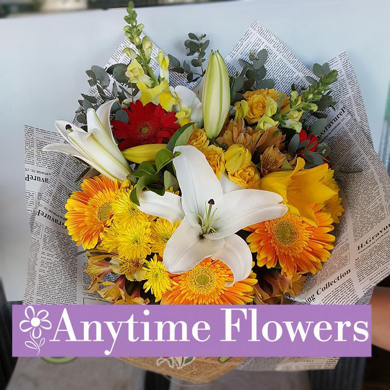 Elegant bouquet with white lilies, orange gerberas, and yellow chrysanthemums in paper wrap.