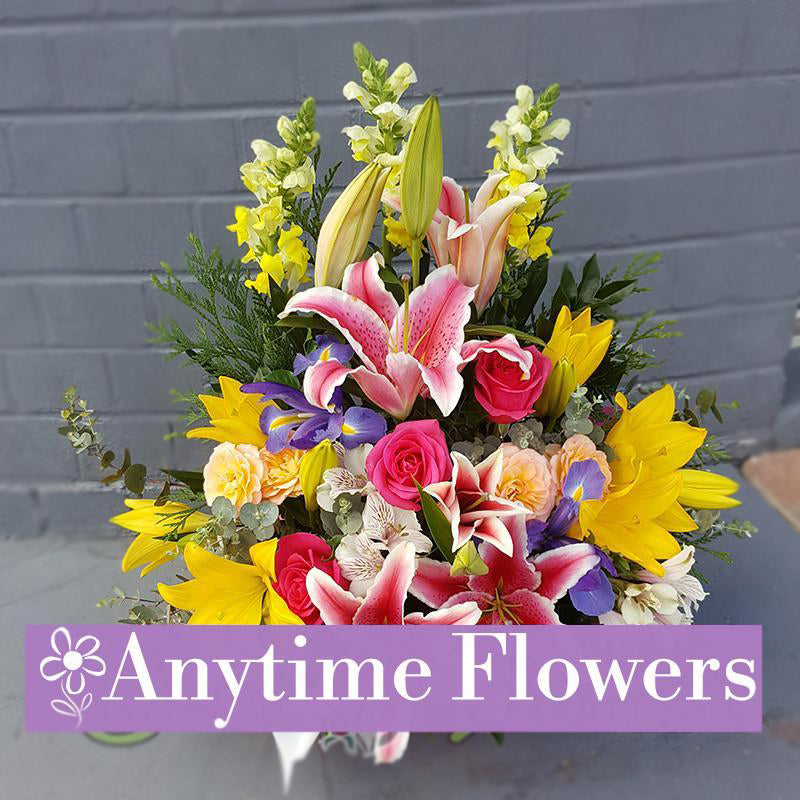 A vibrant bouquet with pink stargazer lilies, yellow sunflowers, pink roses, and purple irises.