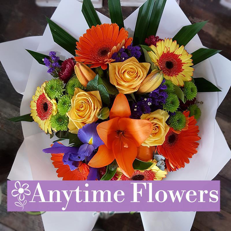 A vibrant bouquet of golden roses, orange lilies, and cheerful gerberas.