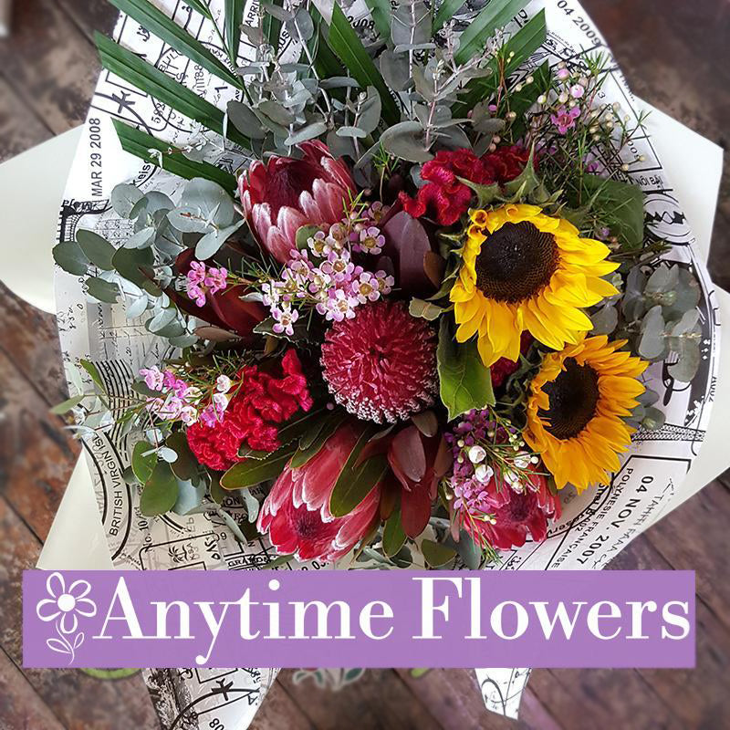 A rustic arrangement of proteas, sunflowers, and native foliage.
