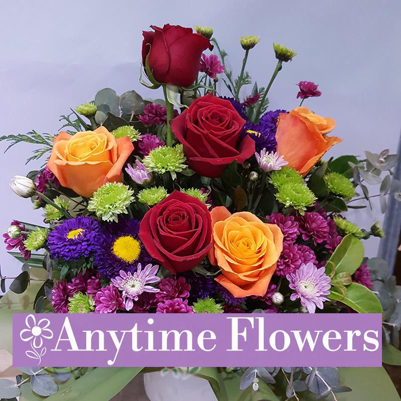 A vibrant arrangement of red, orange, and yellow roses with accent flowers.