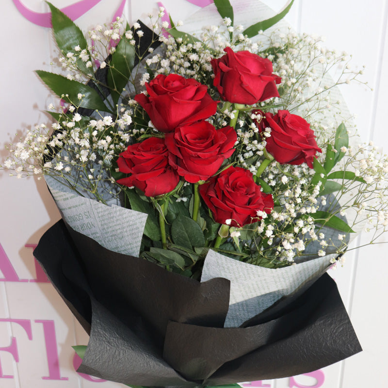 A sophisticated arrangement of vibrant red roses in a sleekbouquet, an ideal heartfelt gift.