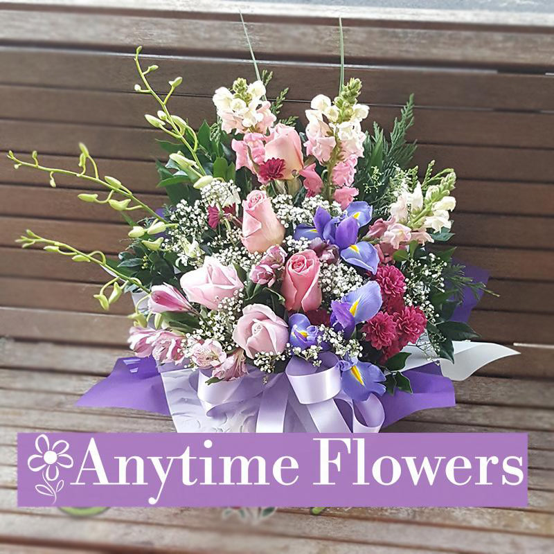 A pastel bouquet of pink roses, vibrant irises, and snapdragons with lush greenery.