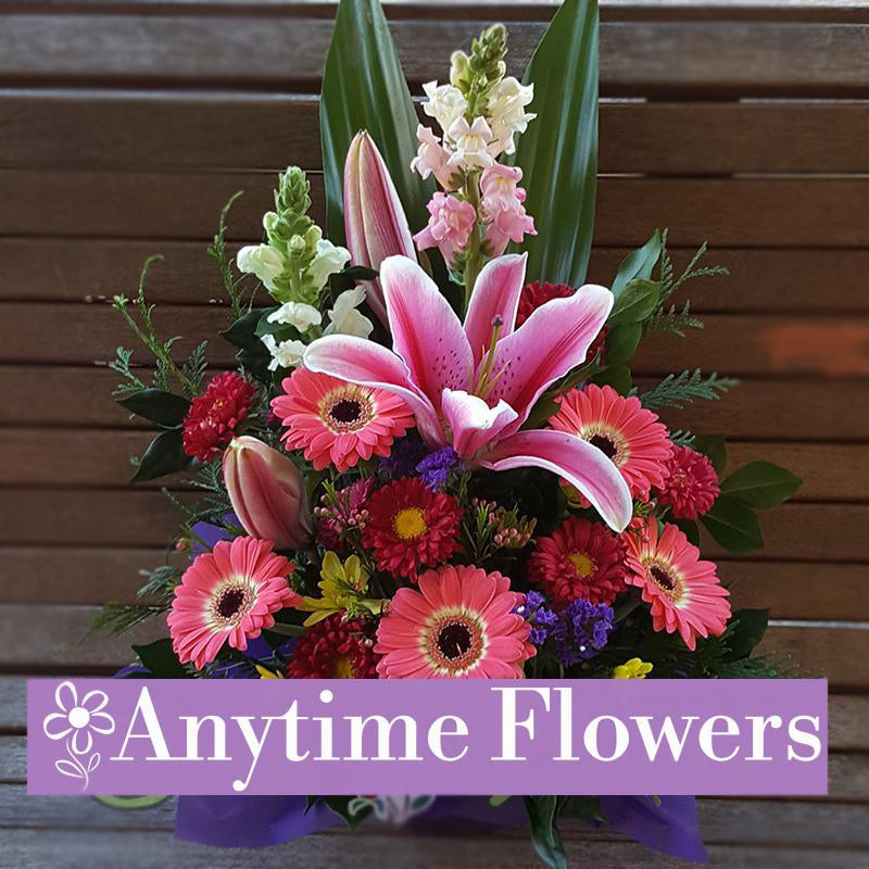 A vibrant bouquet with pink lilies, gerberas, and lush greenery.