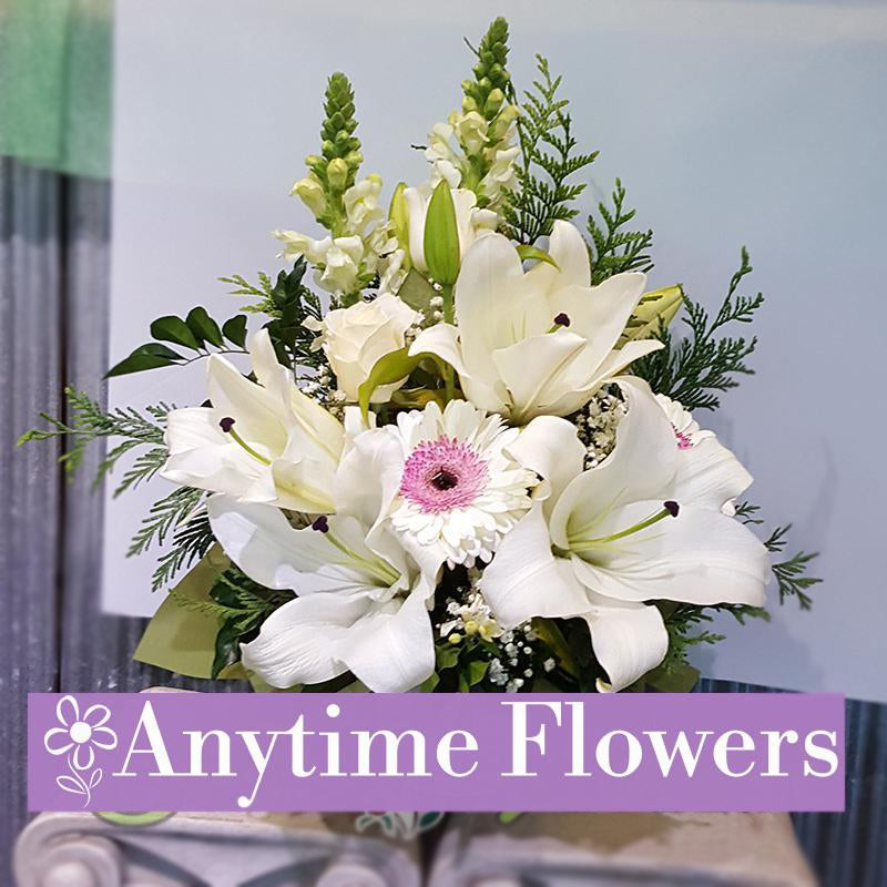 A serene bouquet of white lilies, gerberas, and snapdragons with lush greenery.