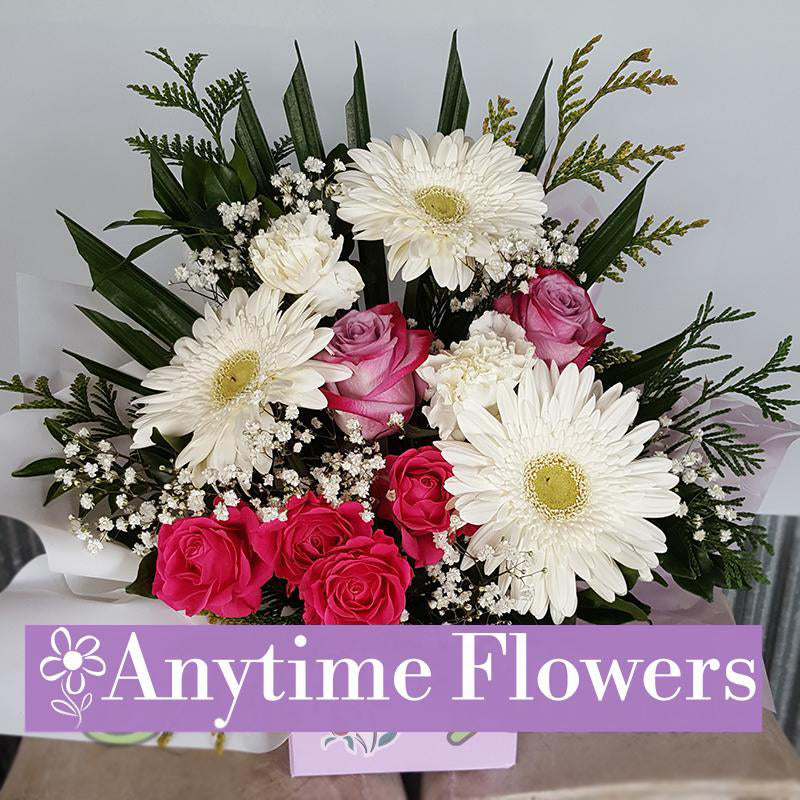A classic arrangement of white gerberas and pink roses with baby's breath and greenery.
