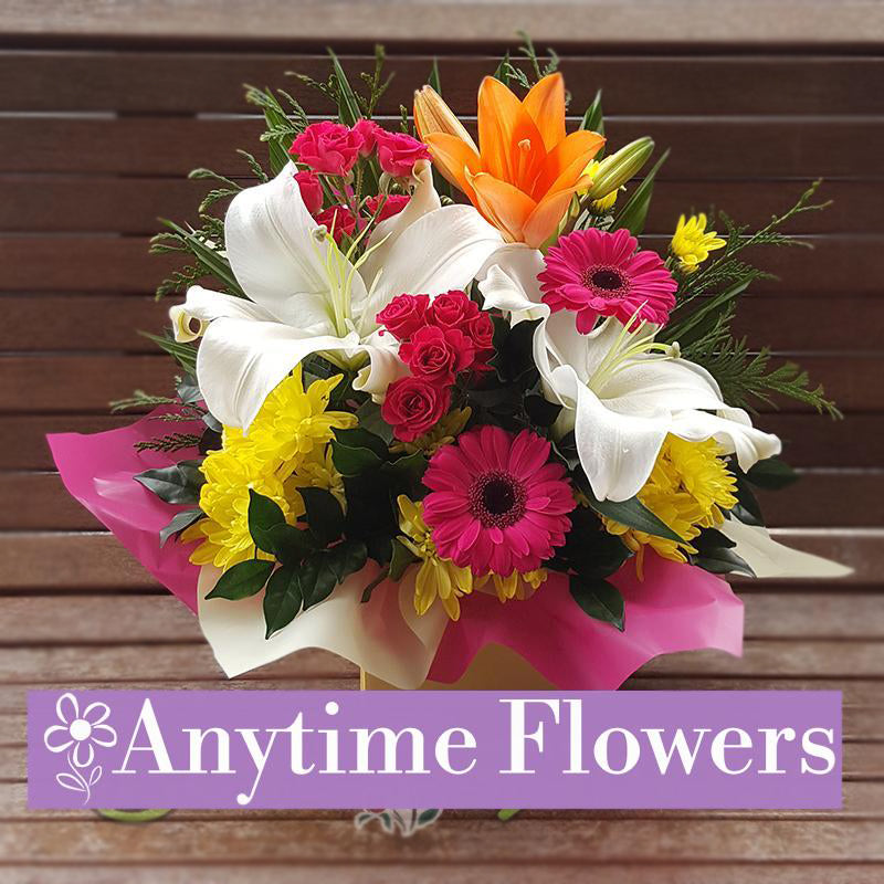 A cheerful bouquet of white lilies, pink gerberas, and yellow chrysanthemums with lush greenery.