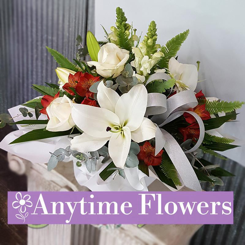 A refined arrangement of white lilies, roses, and snapdragons with red accents and greenery.