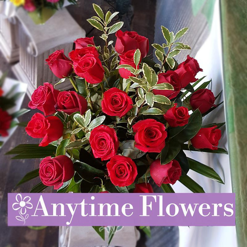 A luxurious bouquet of vibrant red roses accented with lush greenery.