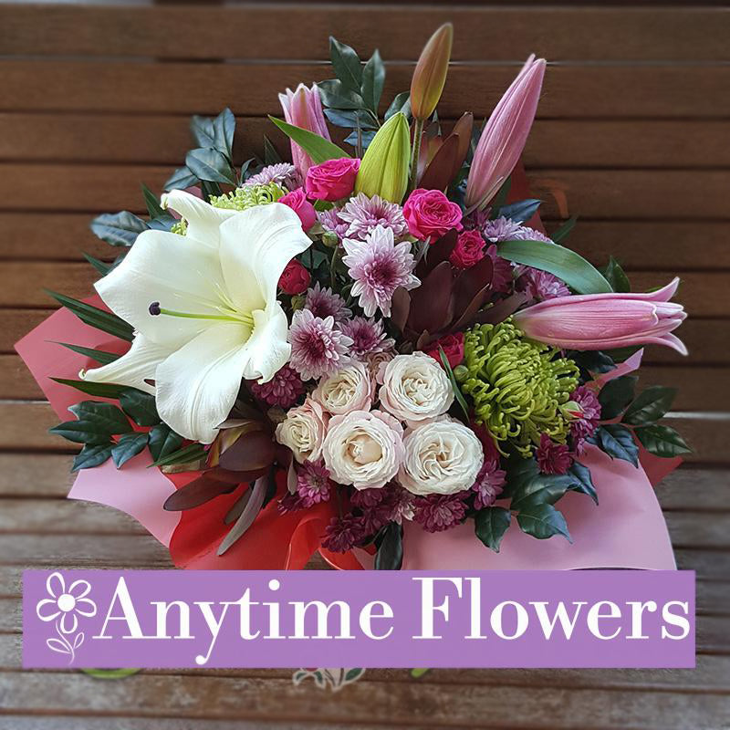 A beautiful arrangement of white lilies, pink roses, and chrysanthemums with lush greenery.