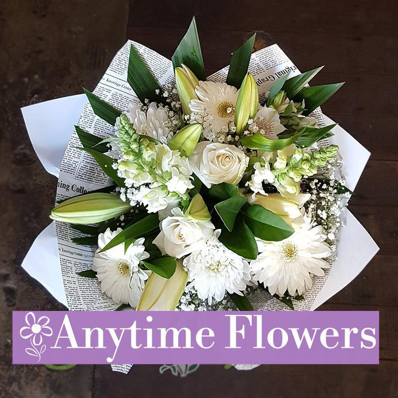 A refined bouquet of white roses, lilies, and snapdragons wrapped in stylish paper.