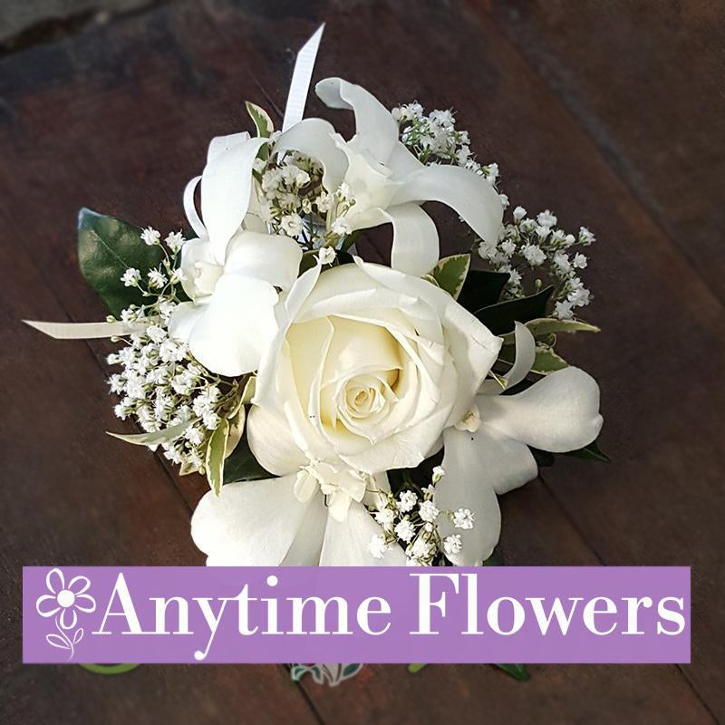A sophisticated corsage with a white rose, orchids, and baby's breath tied with a white ribbon.