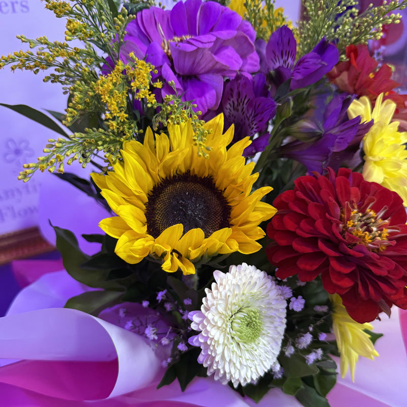 A mini-box featuring a collection of sunflowers, red dahlias, and yellow chrysanthemums, creating a bold and colorful floral arrangement.