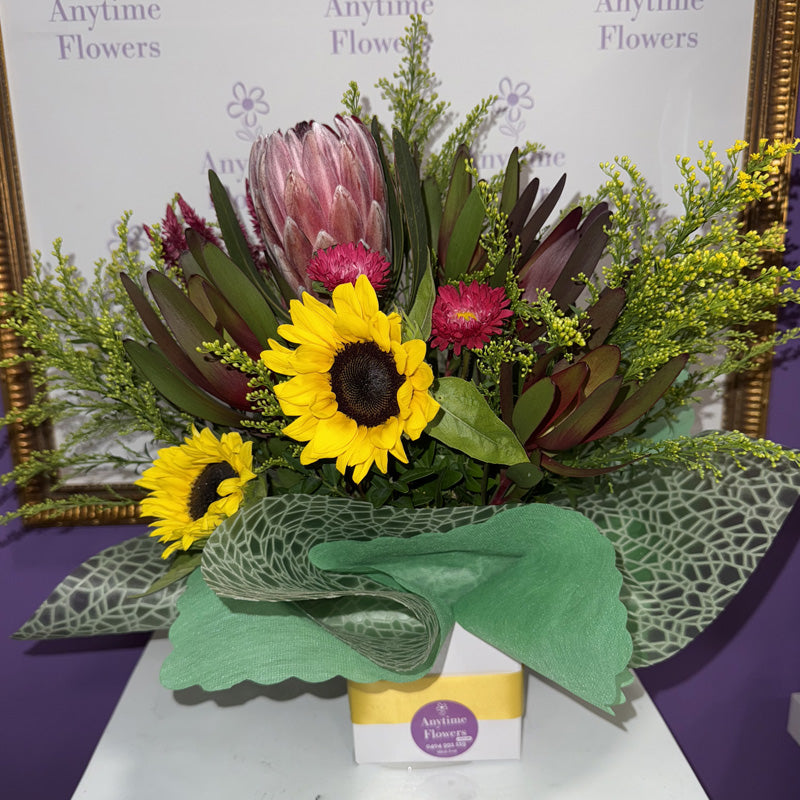 A native flower mini-box featuring proteas, sunflowers, and vibrant red blooms, perfect for celebrating nature's beauty.