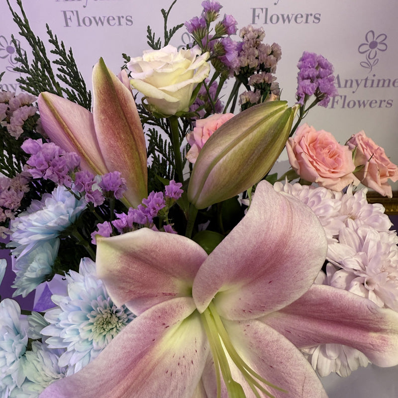 A vibrant mini-box with pink lilies, purple chrysanthemums, and soft pink roses, creating a colorful and elegant display.