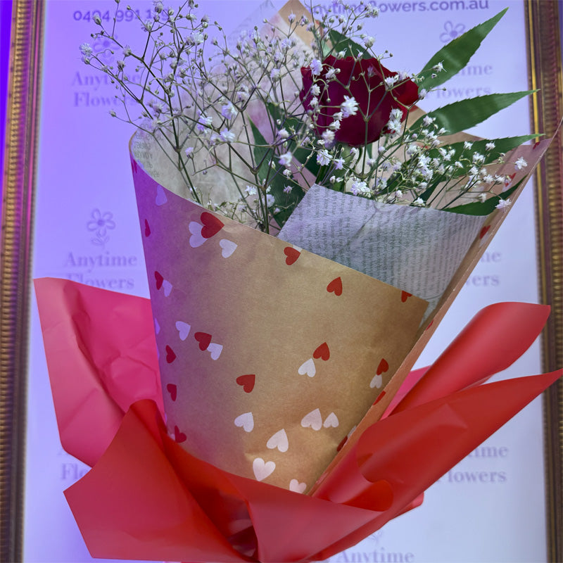 A luxurioussix-rose bouquet arrangement, showcasing deep red roses in a sophisticated black presentation wrap.