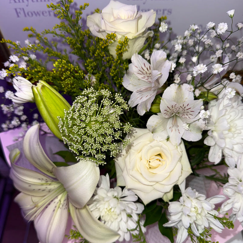 Elegant white flowers including lilies, roses, and gypsophila arranged beautifully in a mini box.