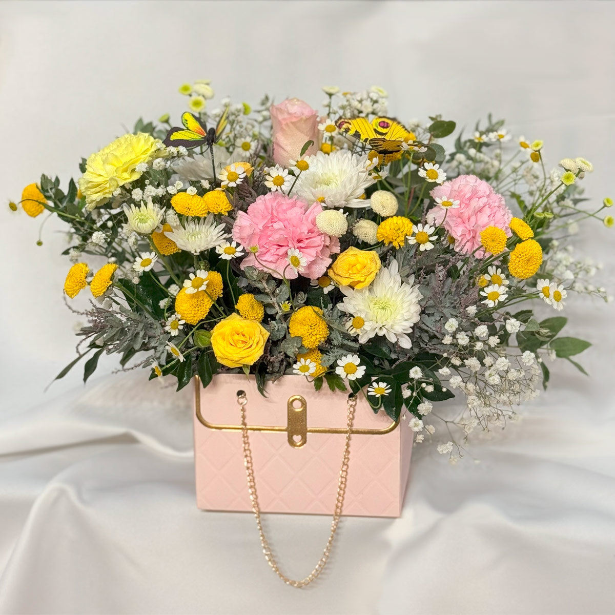 Butterfly garden flower arrangement in pink hand bag box