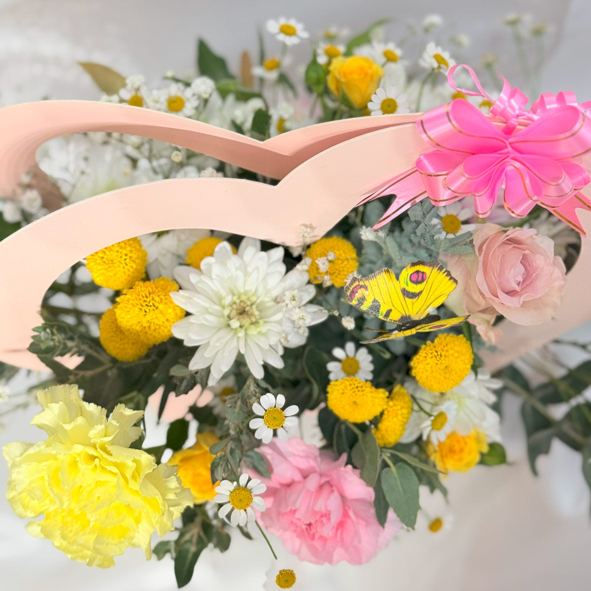Butterfly garden flower arrangement in heart basket close up