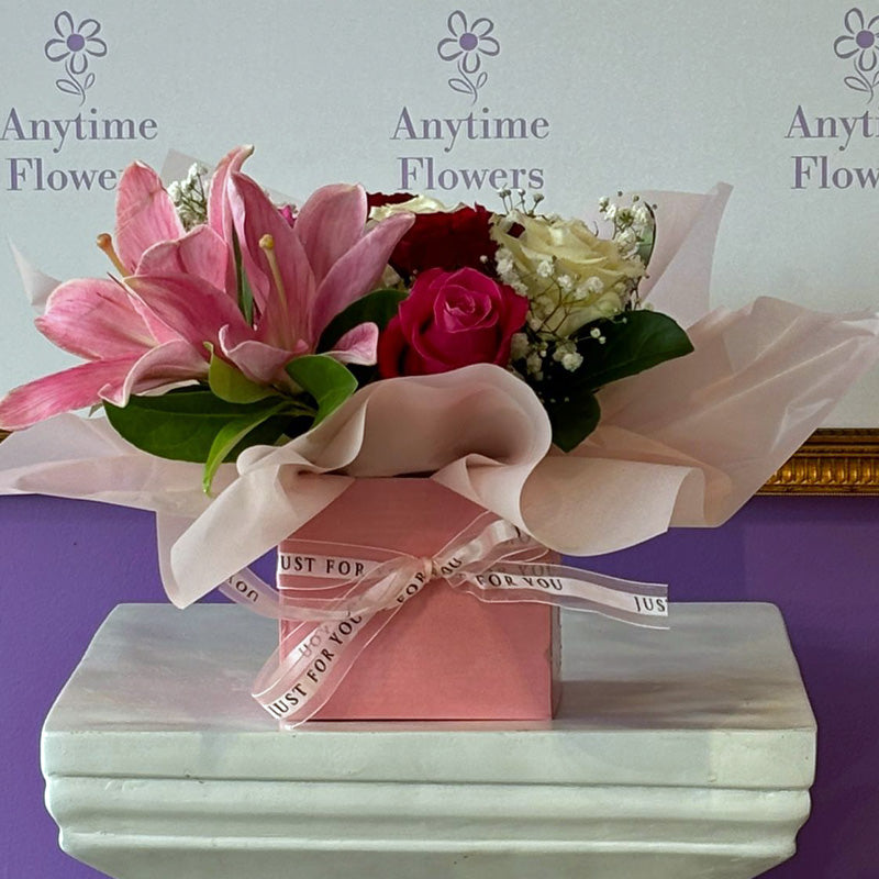Side view of the Lily & Rose Delight Box, elegantly wrapped with soft pink tissue and finished with a satin ribbon, perfect for gifting.