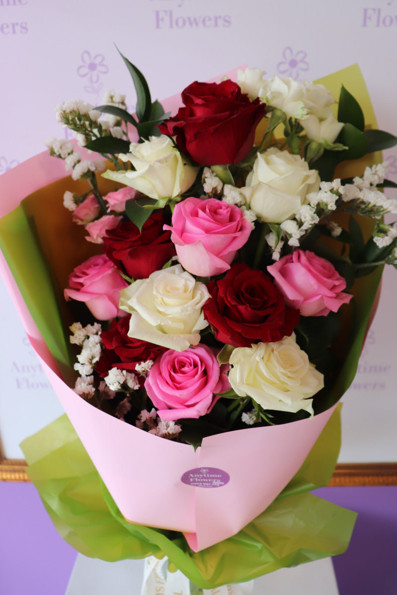 A deluxe rose arrangement in a sleekbouquet, showcasing rich red, pink and white roses in full bloom.