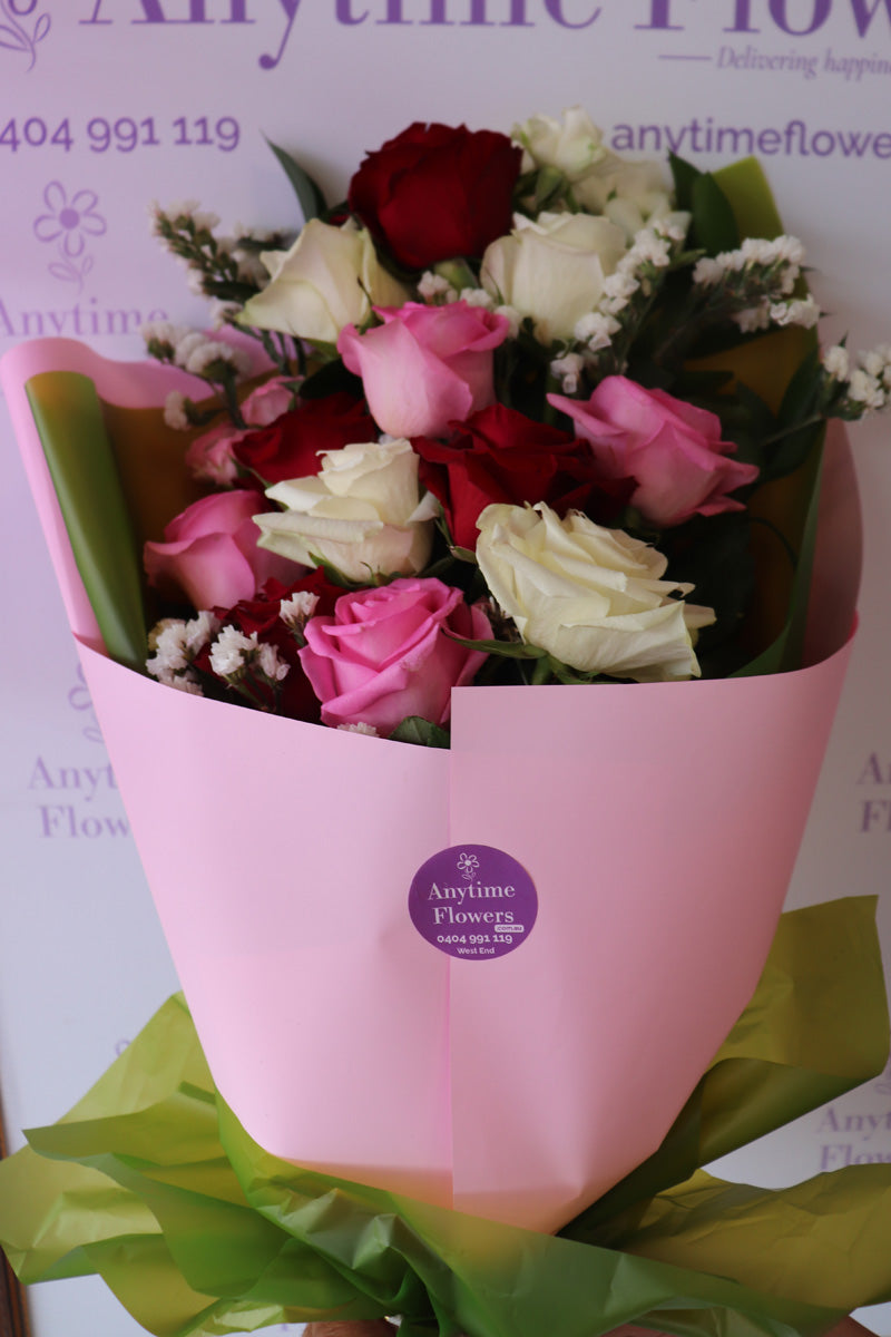 A romanticbouquet featuring a  fresh red, pink and white roses, artistically arranged with lush greenery.