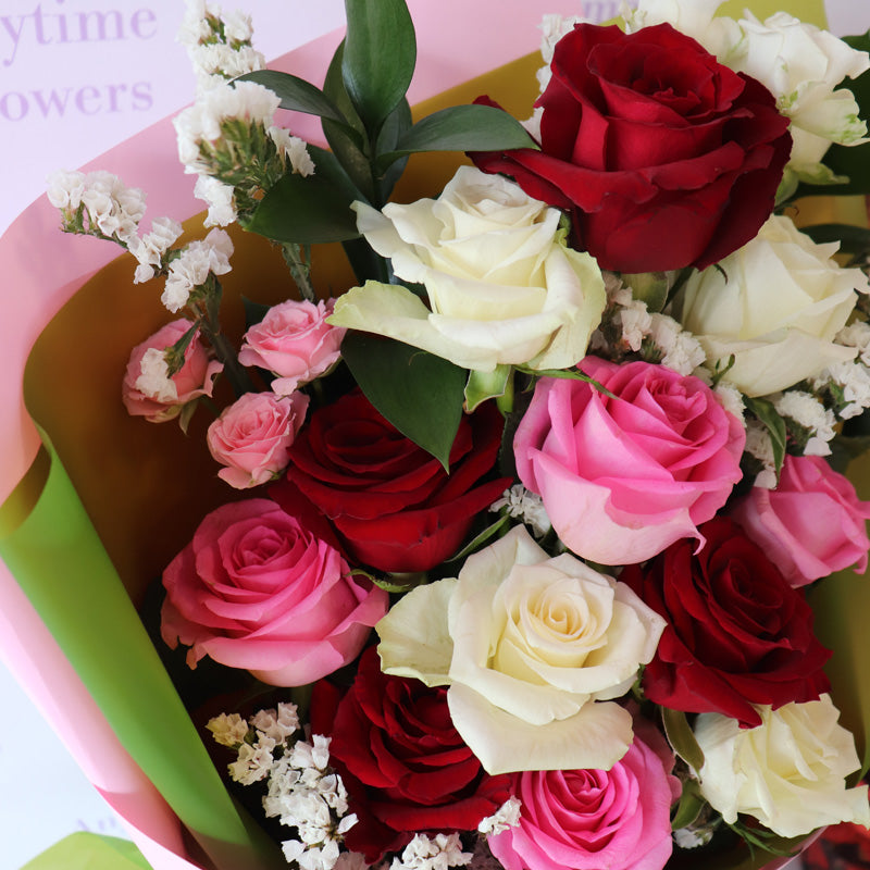 A beautifully arranged bouquet of classic red, white and pink roses, elegantly wrapped with a luxurious black ribbon.