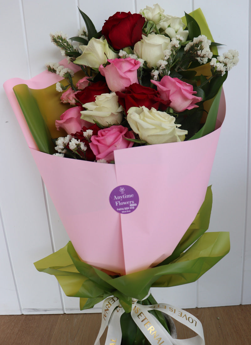 A top view of a classic red, pink and white twelve-rose arrangement in a decorative bouquet, exuding timeless elegance.
