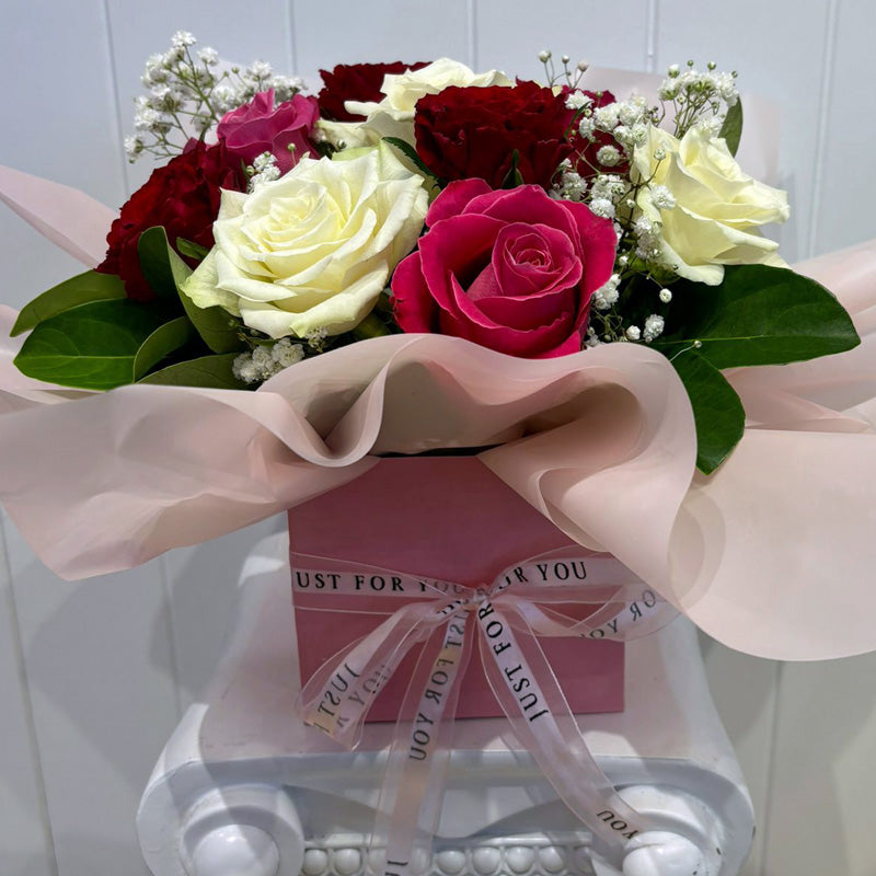 Side view of the Love in Bloom Box, showcasing fresh roses in a pastel pink gift box, finished with an elegant satin ribbon.