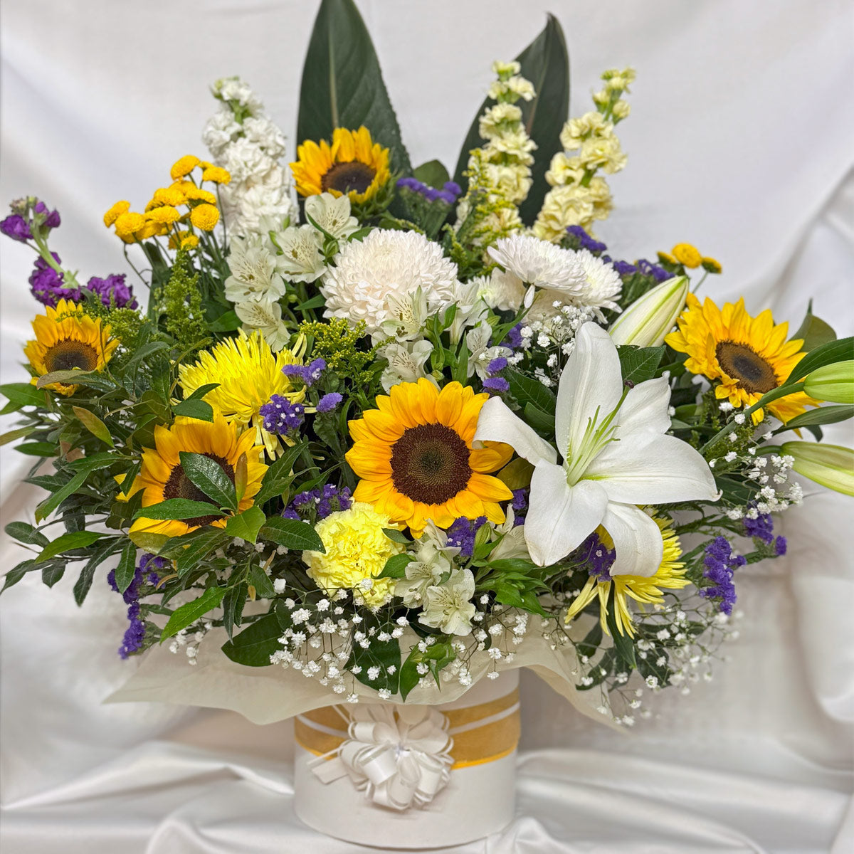 Sunflowers, chrysanthemums and lilies in a bright hatbox arrangement